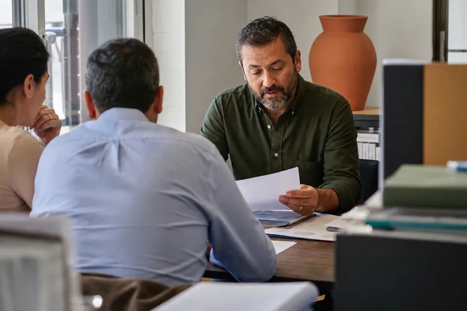 Finance lead reviewing printed papers with colleagues at a meeting table
