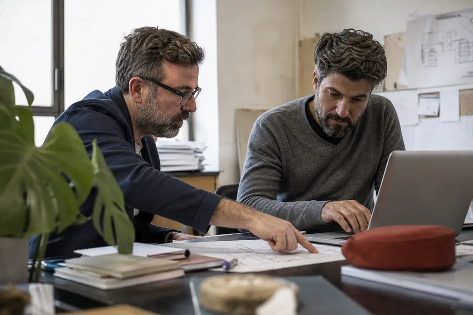 Two senior engineers reviewing a system diagram together in a quiet office
